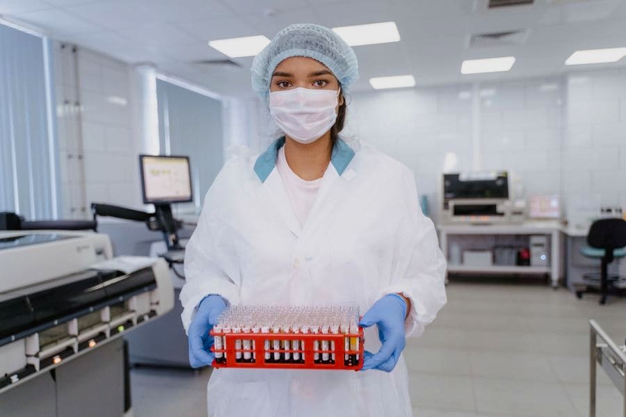 Tecnóloga médica sosteniendo una gradilla con tubos de muestras en un laboratorio clínico