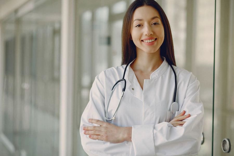 Médica con bata blanca y estetoscopio en el pasillo de un hospital