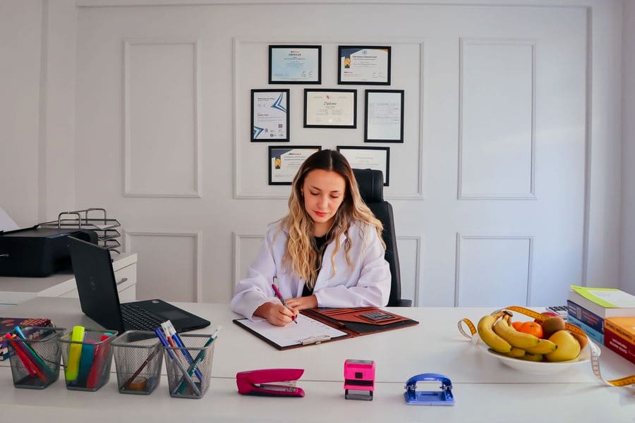 Nutricionista con bata blanca elaborando un plan de alimentación en su consultorio