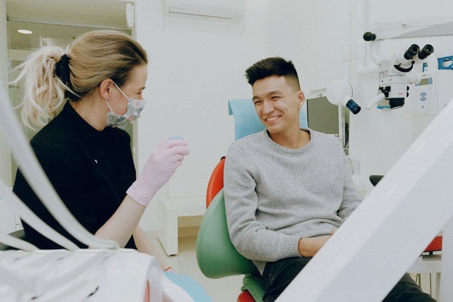 Odontóloga atendiendo a un paciente sentado en el sillón dental de una clínica